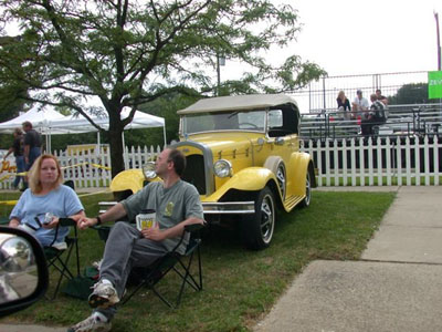 2001 Ford Crown Victoria - A yellow prewar open touring car with a tan folding soft top, wire-look wheels with wide whitewall tires, exposed side-mount spare and chro…