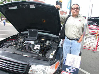 2001 Ford Crown Victoria - A black Ford Crown Victoria displayed at an outdoor event with the hood raised, showing a modular V8 with polished intake tubing and a lapt…
