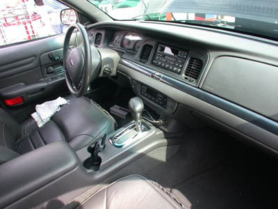 2001 Ford Crown Victoria - Interior of a Ford Crown Victoria shot from the driver's door, showing gray leather bucket seats, a console-mounted automatic shifter with…