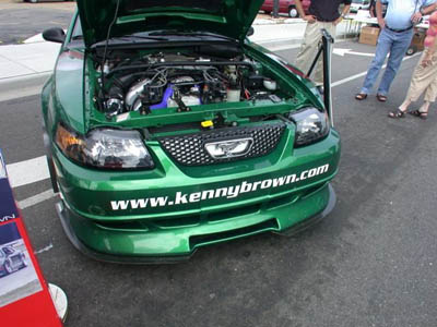 2001 Ford Crown Victoria - Candy green SW-body Ford Mustang displayed at an outdoor car show with the hood up, front three-quarter view showing a chrome mesh grille,…