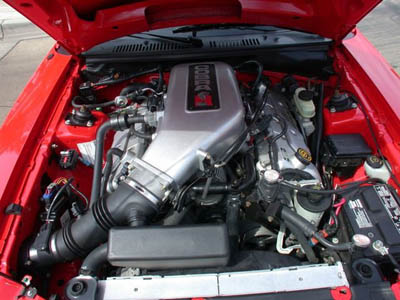2001 Ford Crown Victoria - Engine bay of a red car with the hood up, showing a DOHC 4.6L V8 with cast aluminum intake, black plastic engine cover and ribbed valve cov…