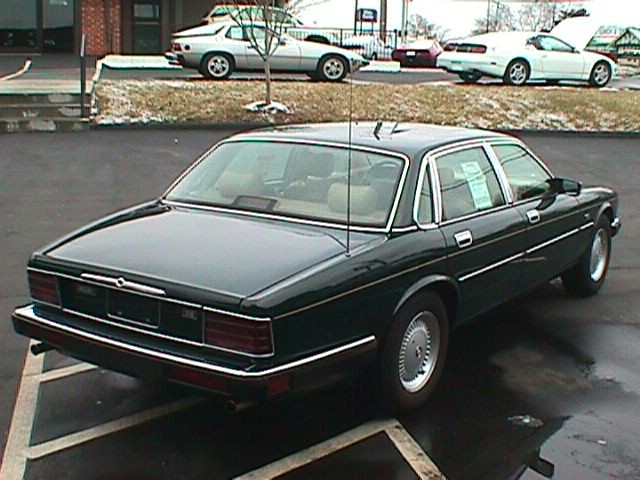 Dark green Jaguar XJ6 sedan seen from rear 3/4 angle in a parking lot