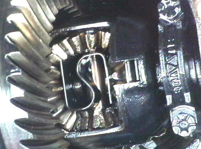 Close-up of differential spider gears with S-shaped cross shaft retaining clip and ring gear teeth