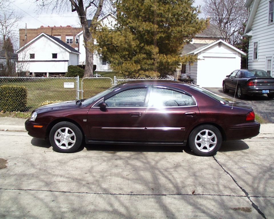 Maroon four-door sedan parked in driveway, driver's side profile view