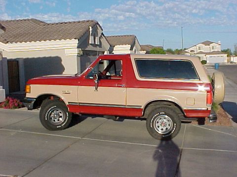 1988 Ford Bronco - This 1988 Ford Bronco features a two-tone red and tan paint scheme and a rear-mounted spare tire.