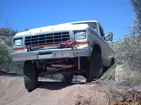 1979 Ford Bronco - Ford F-Series truck navigating an off-road incline under a clear blue sky.