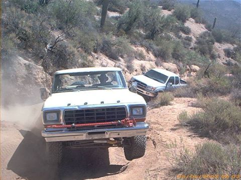 1979 Ford Bronco - A 1979 Ford Bronco leads a silver pickup truck up a steep, dusty desert incline.