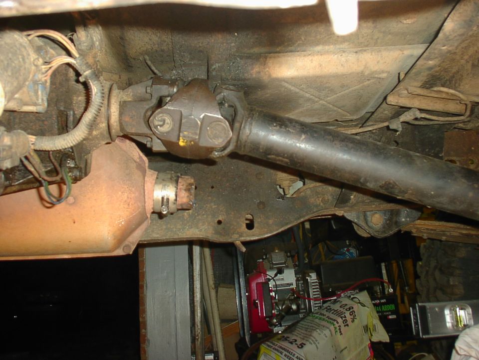 Underbody view of driveshaft U-joint and exhaust pipe on a Ford Bronco in a garage