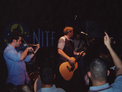 1989 Ford Bronco - A band plays live music on stage in front of a neon sign.