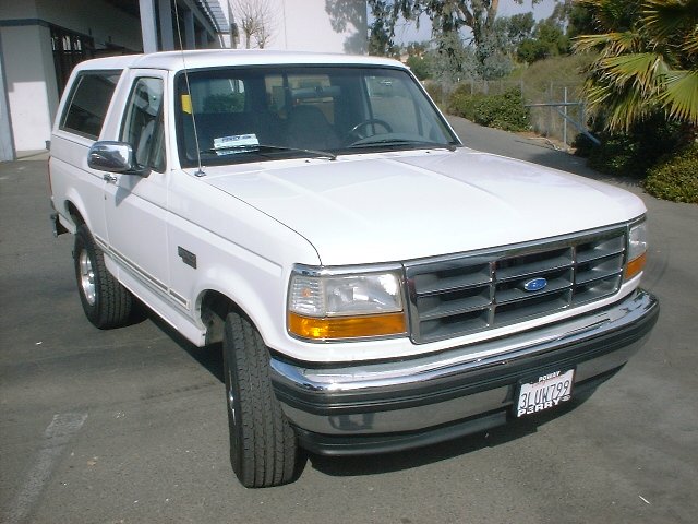 Front three-quarter view of white two-door Ford Bronco with chrome bumper and California plate