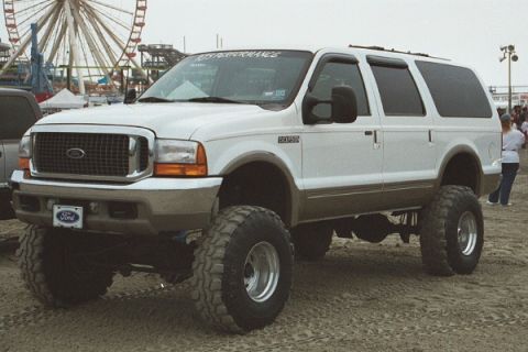 2001 Ford Excursion - This lifted Ford Excursion is parked on sandy ground with a Ferris wheel in the background.