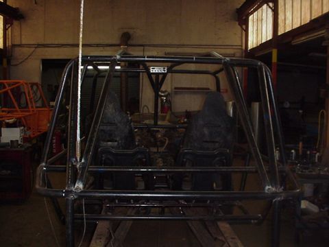 1979 Ford Bronco - Interior view of a custom roll cage and seats within a workshop setting.