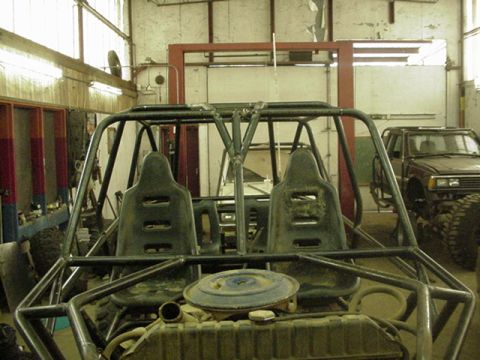 1979 Ford Bronco - Interior view of a custom off-road buggy with a truck visible in the background of a workshop.