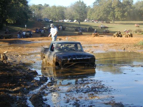 1979 Ford Bronco - A 1979 Ford Bronco is stuck in a muddy field with other vehicles and people in the background.