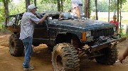 1979 Ford Bronco - An off-road vehicle, heavily modified for rough terrain, is being examined by several people.