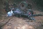 1979 Ford Bronco - An SUV has overturned in a muddy terrain, with a person lying on the ground next to it.