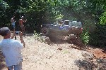 1979 Ford Bronco - A person films an off-road vehicle navigating a steep, sandy incline surrounded by trees.