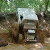 1979 Ford Bronco - An off-road vehicle powers through a challenging muddy terrain, kicking up water and dirt.