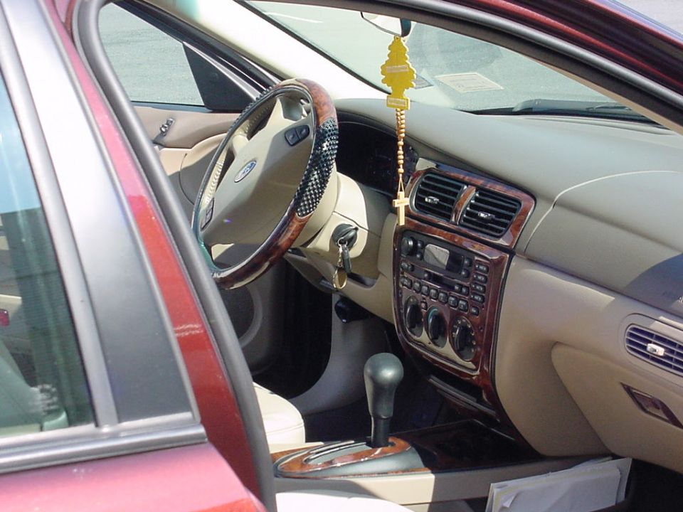 Tan Ford Taurus interior with woodgrain dash trim seen through the open driver's door