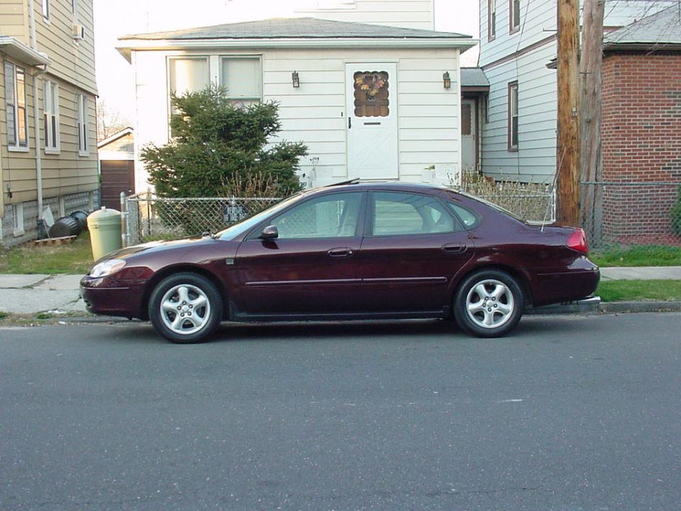 Maroon four-door sedan parked curbside, driver-side profile view