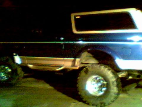 1996 Ford Bronco - Side view of a dark-colored SUV with a white removable top, consistent with a 1996 Ford Bronco.