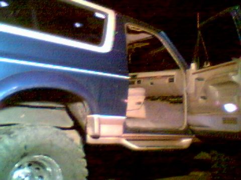 1996 Ford Bronco - The interior of a blue SUV is visible with the driver's side door ajar, revealing the seats and dashboard area.