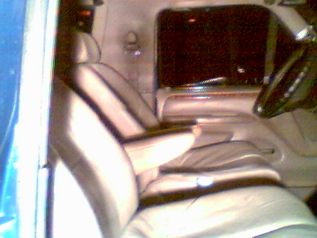 Blurry view of a tan leather interior with bucket seat and rear bench