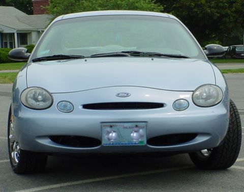 1998 Ford Taurus - The front of a light blue sedan is shown, its headlights, grille, and license plate.
