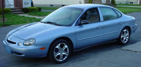 1998 Ford Taurus - The 1998 Ford Taurus sedan is viewed from the front three-quarter angle, parked on a residential street.