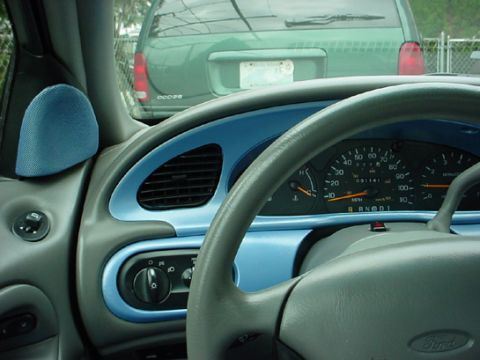 1998 Ford Taurus - Interior view of a car's dashboard and steering wheel, with a green van in the background.