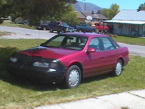 1995 Ford Taurus - This 1995 Ford Taurus sedan is shown in a 3/4 front view, parked on a grassy lawn with a black car bra covering the front end.