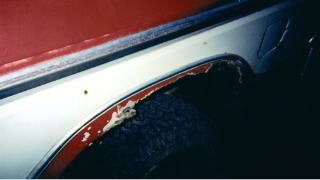 1978 Ford Bronco - Close-up view of the rear fender well of a vehicle, showing signs of wear and tear.