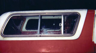 1978 Ford Bronco - Side view of a red and white vehicle, its windows and camper shell.