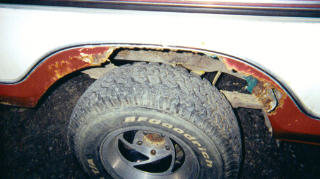 1978 Ford Bronco - Close-up of severe rust damage on the rear wheel well of a vehicle.