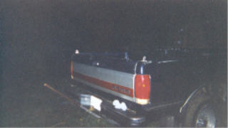 1990 Ford F-150 - The rear of a Ford F-150 pickup truck is visible at night, with its tailgate illuminated.