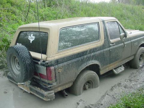 1990 Ford Bronco - This 1990 Ford Bronco is deeply stuck in mud, with its rear-mounted spare tire partially submerged.