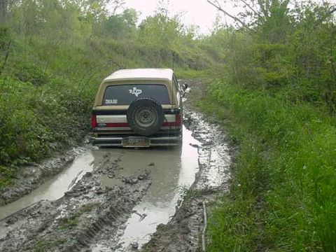 1990 Ford Bronco - Ford Bronco navigating a difficult muddy path off-road.
