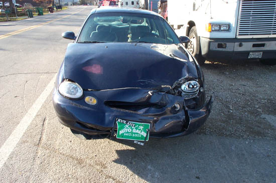 Front view of a damaged 1996 Ford Taurus with a green "RVR AUT" license plate