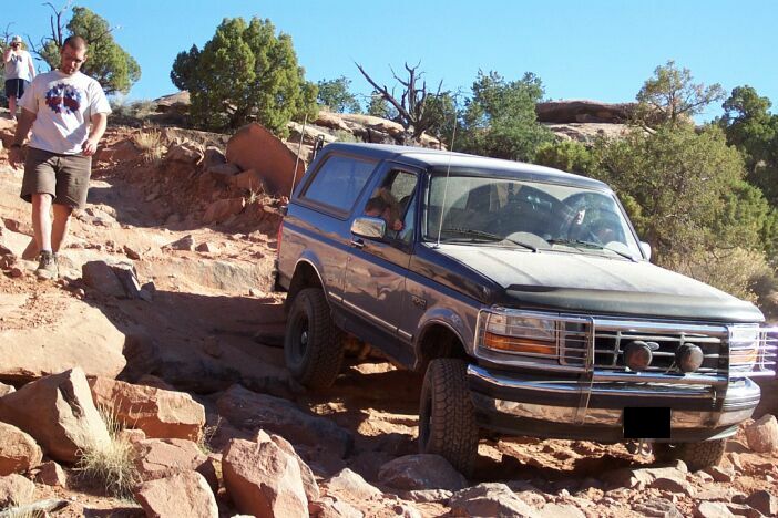 Dark blue Ford Bronco on a rocky off-road trail, front grille visible