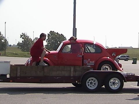 1998 Ford Taurus - A red Volkswagen Beetle is being transported on a trailer, with two people interacting with the car.