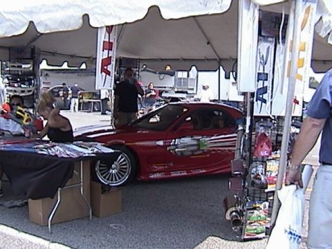 1998 Ford Taurus - A red sports car with distinctive graphic decals is displayed under a tent at an outdoor event.