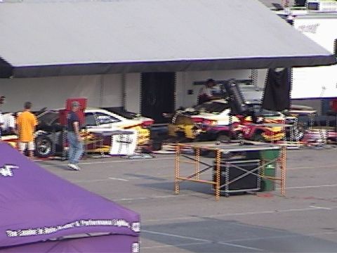 1998 Ford Taurus - Multiple race cars are visible under a large canopy, with equipment and people around them.