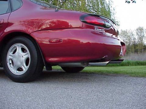 1998 Ford Taurus - The rear passenger side of a red sedan, showing the wheel and dual exhaust pipes.