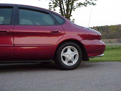 1998 Ford Taurus - Rear side view of a red 1998 Ford Taurus sedan parked on asphalt.