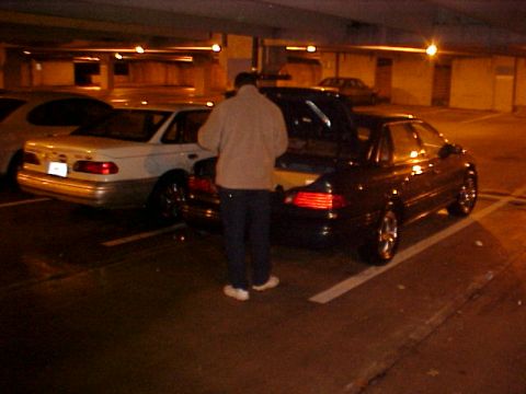 2001 Ford Taurus - Two sedans are parked in a dimly lit garage, with one vehicle's trunk open.