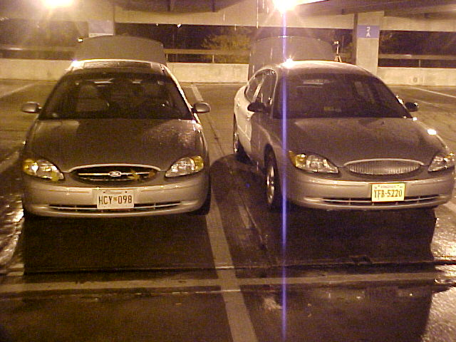 Two silver Ford Taurus sedans parked in a parking garage at night