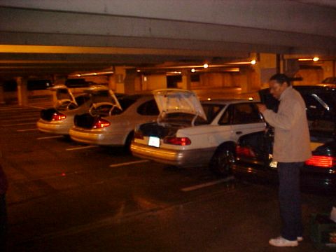 2001 Ford Taurus - Multiple sedans are parked in a dimly lit garage, with several trunks open, suggesting activity or loading.