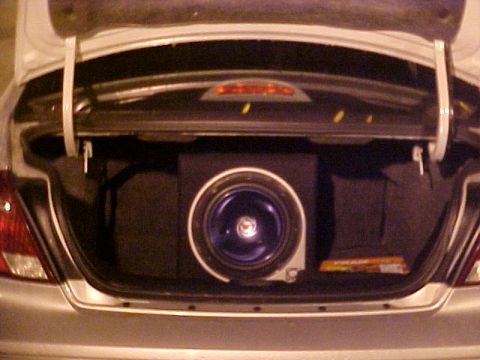 2001 Ford Taurus - The trunk of a car is open, revealing a subwoofer and speaker system installed.