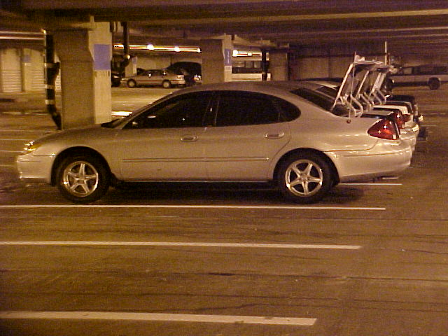 Silver 2001 Ford Taurus parked in a garage, side view. Another car is parked behind it