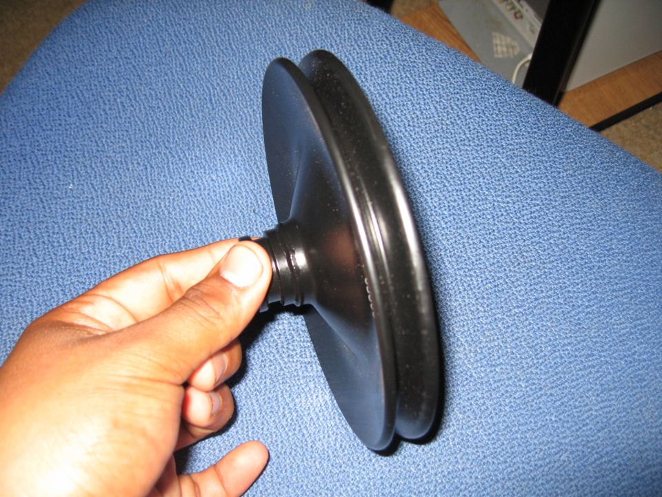 Hand holding a black cone-shaped dished part with ribbed hub collar over a blue chair